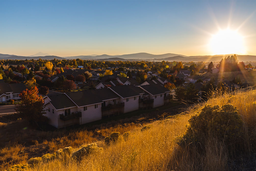 Bright sunshine in a clear sky over a row of houses during fall.